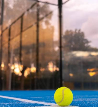 Vertical shot of a paddle tennis court at sunset with a ball on the surface on the line paddle tennis court